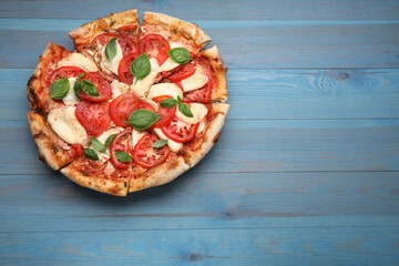 Delicious Caprese pizza on blue wooden table, top view. Space for text