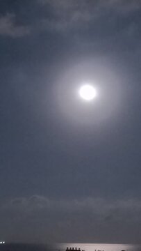 full moonrise over the sea in the clouds over the seaside city. timelapse