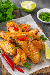 Baked chicken wings served with sweet chili sauce and fresh herbs. Selective focus.