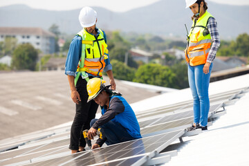 Electrical engineering man using electric hand drill to Installing Solar Cell panels on Roof. Solar...
