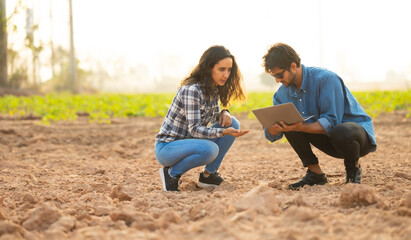 Fototapeta premium Hispanic man and woman Farmer holding soil in hands checking soil quality before sowing data on laptop computer. Agriculture. Plantation and gardening concept