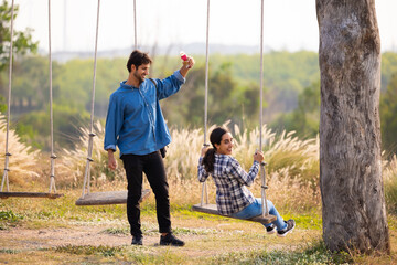 Obraz premium romantic couple in love sitting on rope swing. love, relationship. Hispanic latin male and woman