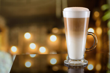 Glass mug of latte coffee on the bar counter with blurred background. Copy space. - obrazy, fototapety, plakaty