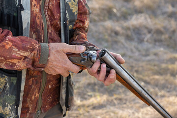 Midsection of man unloading shotgun while standing on field