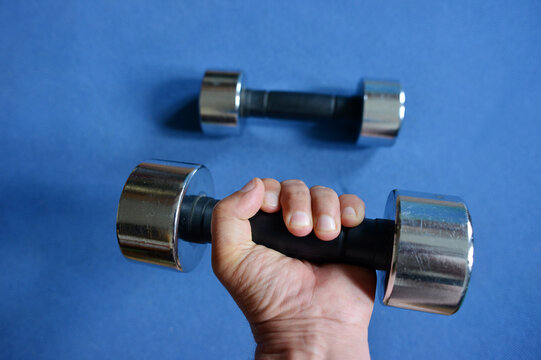 Hand lifting a dumbbell on a blue yoga mat