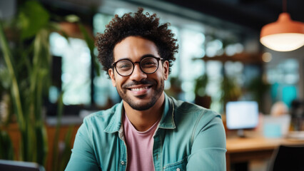 Portrait of a multi-ethnic young man with glasses. IT specialist standing in the center of a cozy corporate office.