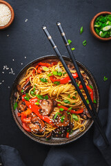 Stir fry noodles with vegetables: red paprika, champignons, green onion and sesame seeds in ceramic...