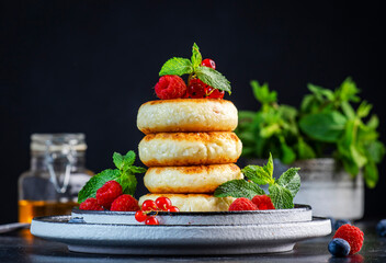 Thick cottage cheese pancakes with blueberries, raspberries and red currants, decorated with fresh...