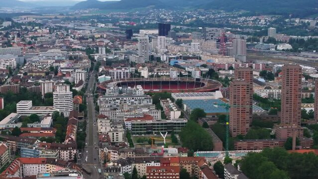 Elevated slide and pan shot of Letzigrund football and athletic stadium surrounded by apartment houses in city. Zurich, Switzerland