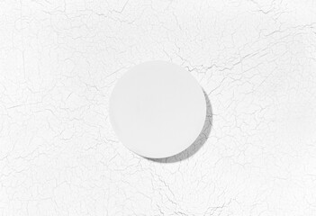 Flat lay cosmetic product presentation scene made with round pedestal on craquelure background. Studio photography, top view.