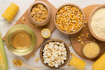 Maize products with fresh corn cobs on wooden background, top view