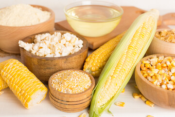 Maize products with fresh corn cobs on wooden table