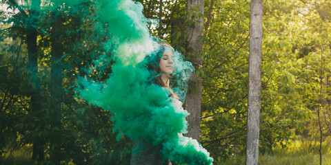 Girl with smoke bomb makes saturated green clouds of smoke.