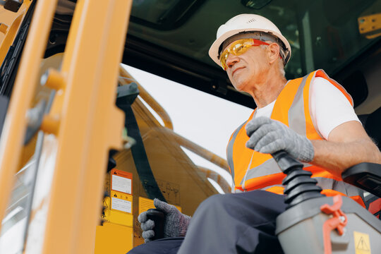 Industry worker portrait. Man driver builder operate crane or excavator at construction site