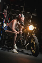 Fototapeta na wymiar Girl with the repair tool near the old motorbike in the garage concept.