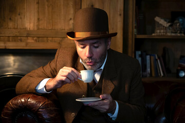 A man in a Victorian hat and suit drinks coffee from a white porcelain cup in a retro-style salon.