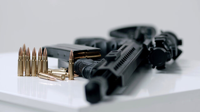 High angle dolly in towards loaded assault rifle with a small amount of ammunition in the foreground. military target, war, bullet weapon, army military firearm, bunch of bullets, bullet shells, milit