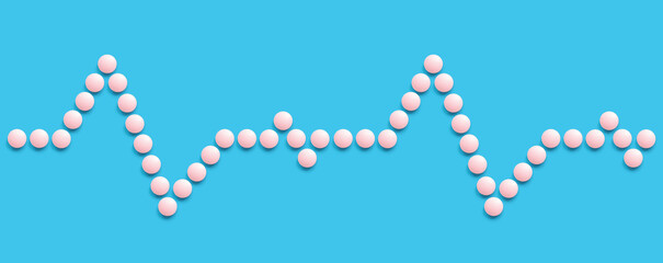 A group of pink round pills form a figure on a blue background. Pulse. The theme of healthcare, treatment and prevention of diseases. World Heart Day