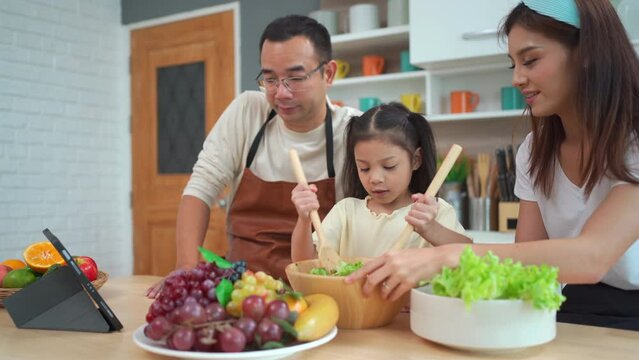 Happy Asian family enjoy making a salad together.