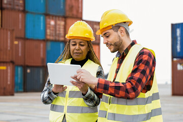 Industrial workers using computer tablet for container shipping control at warehouse storage outdoor - Delivery site concept - Focus on senior African woman face