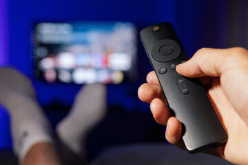 hand with tv remote control. man watching streaming service content at home