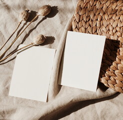Cards mockup, dried twigs and sunlight shadow on beige  linen texture background top view flatlay. Blank, greeting card with copy space. Neutral colors.