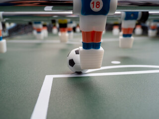 A close-up of some players and a soccer ball on a foosball table. Board game football.