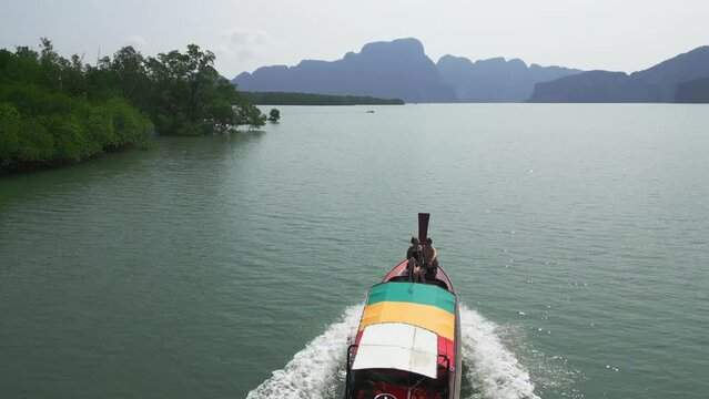 Happy couple floating on Asian river traditional boat longtail sea mountain island enjoy romantic date aerial view. Drone follow shot man and woman travel together exotic water transport seascape 4k