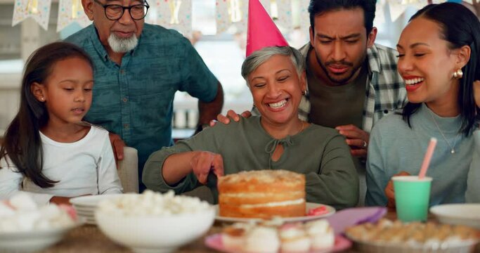 Birthday, party and a senior woman with her family at home together in celebration of a life milestone event. Kids, parents and grandparents with cake in a house to celebrate an elderly grandma