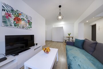 Nowoczesny apartament z zielona sofą, telewizorem i otwartą kuchnią - obrazy, fototapety, plakaty