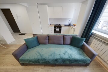 Nowoczesny apartament z zielona sofą, telewizorem i otwartą kuchnią - obrazy, fototapety, plakaty