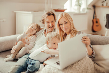 Young family using a laptop while sitting on the couch in the living room