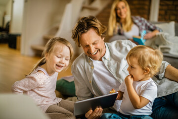 Family playing and using a tablet in the living room at home
