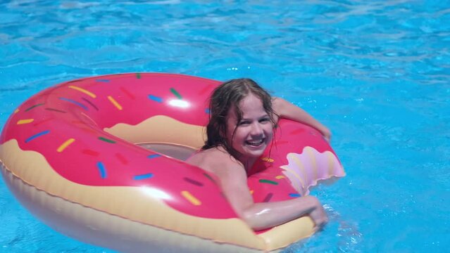 Happy kid girl playing in swimming pool with inflatable lap. Summer family vacations concept