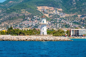 Alanya lighthouse on Alanya houses, beaches and mountain hills background at sunny day. Old lightshouse Alanya sea view