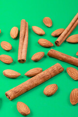 Almonds and cinnamon sticks on a green background.