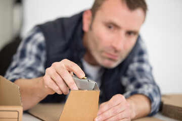 male worker cutting cardboard with a craft knife