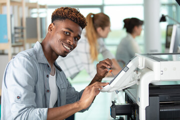 Fototapeta premium young man repair printer with two women on background