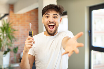 young handsome man smiling happily and offering or showing a concept. new home key concept