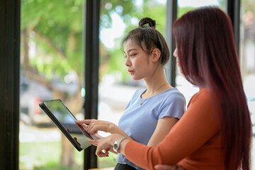Fototapeta premium Two Young businesswomen talk, consult, discuss working with new startup project idea.