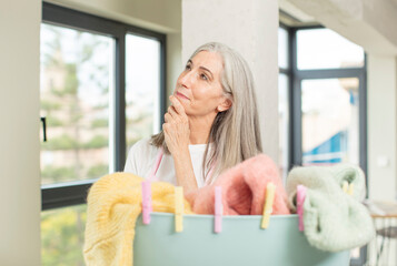 pretty senior woman smiling with a happy, confident expression with hand on chin. washing clothes concept