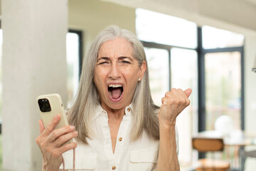 pretty senior woman looking angry, annoyed and frustrated. smartphone concept