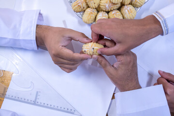 Arabic working colleagues hands  eating eid kahk together on working desk