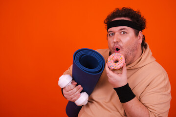 Funny fat man in the gym doing fitness and eating donuts.