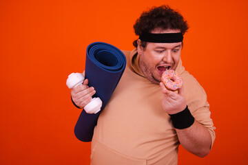 Funny fat man in the gym doing fitness and eating donuts.