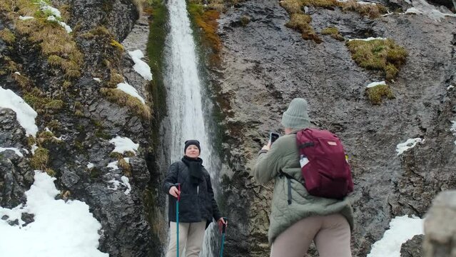 Woman makes photos near the mountain waterfall in winter, 4k