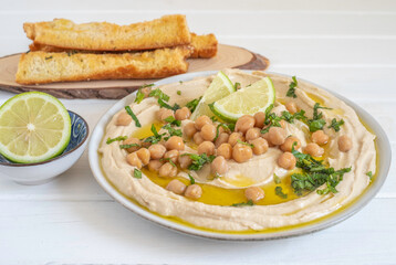Chickpeas and fresh mint on hummus plate over white wooden background.