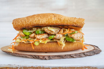 Sandwich with turkey meat, hot pepper and coleslaw on wooden background.