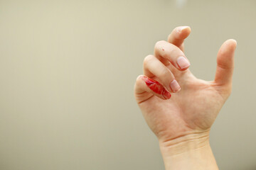 Female hand with red blood, little finger is bleeding profusely. Woman injured her little finger at...