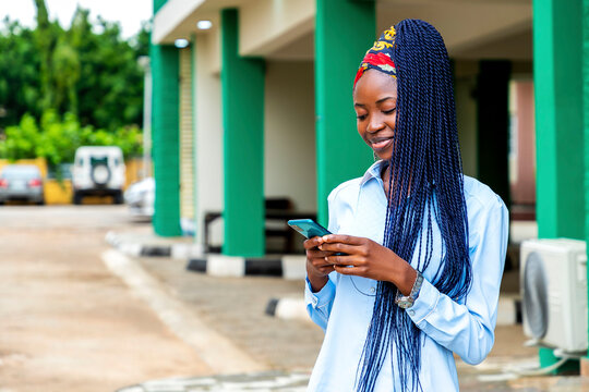 African woman with blue cornrows using a cell phone